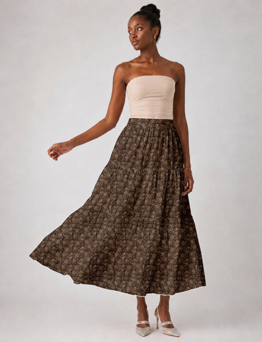 Woman wearing a yellow midi tiered skirt with a small geometric pattern, paired with a beige strapless top and white heels
