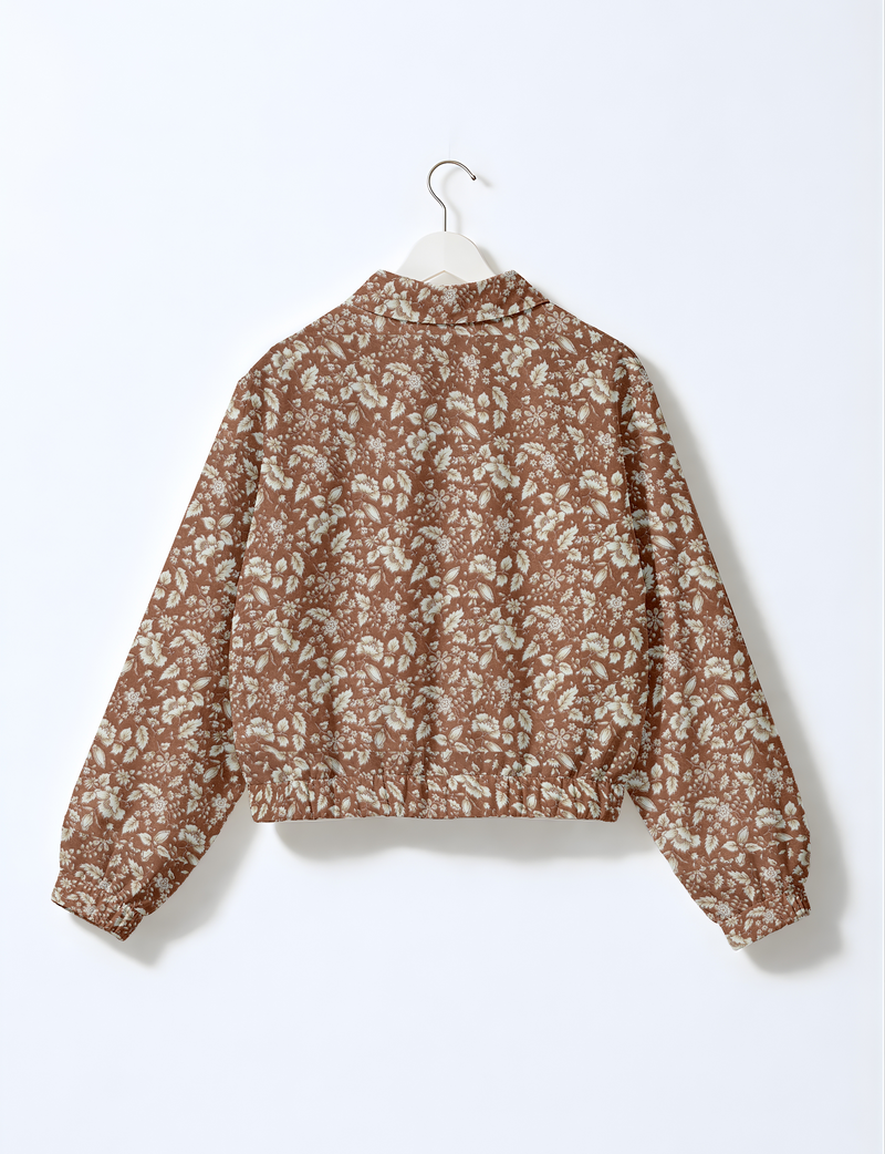 Brown bomber jacket with white floral pattern, elastic cuffs and waistband, shown from back on white hanger