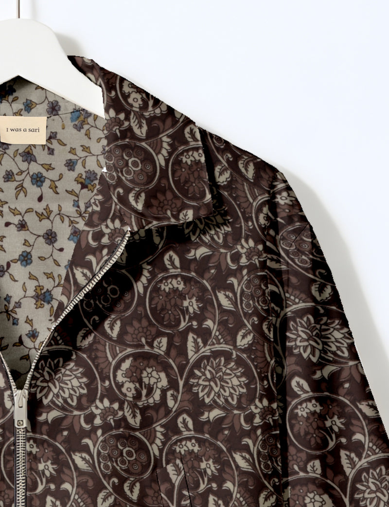 Brown floral patterned bomber jacket with front zipper, shown hanging with visible inner lining and label "I was a sari"