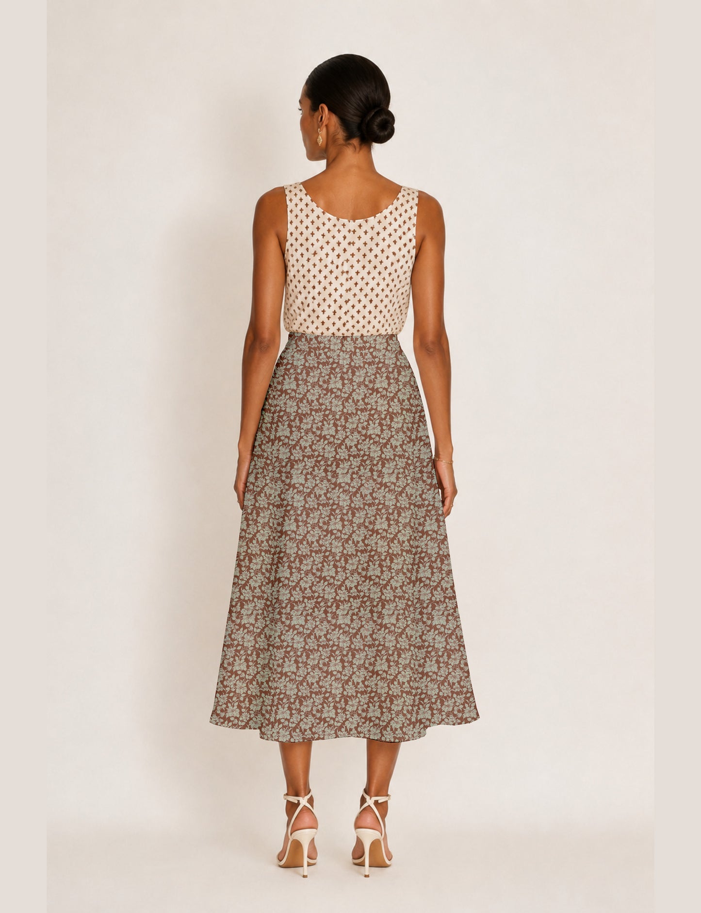Woman wearing a yellow and black micro patterned A-line skirt with front slit, paired with beige sleeveless top and black