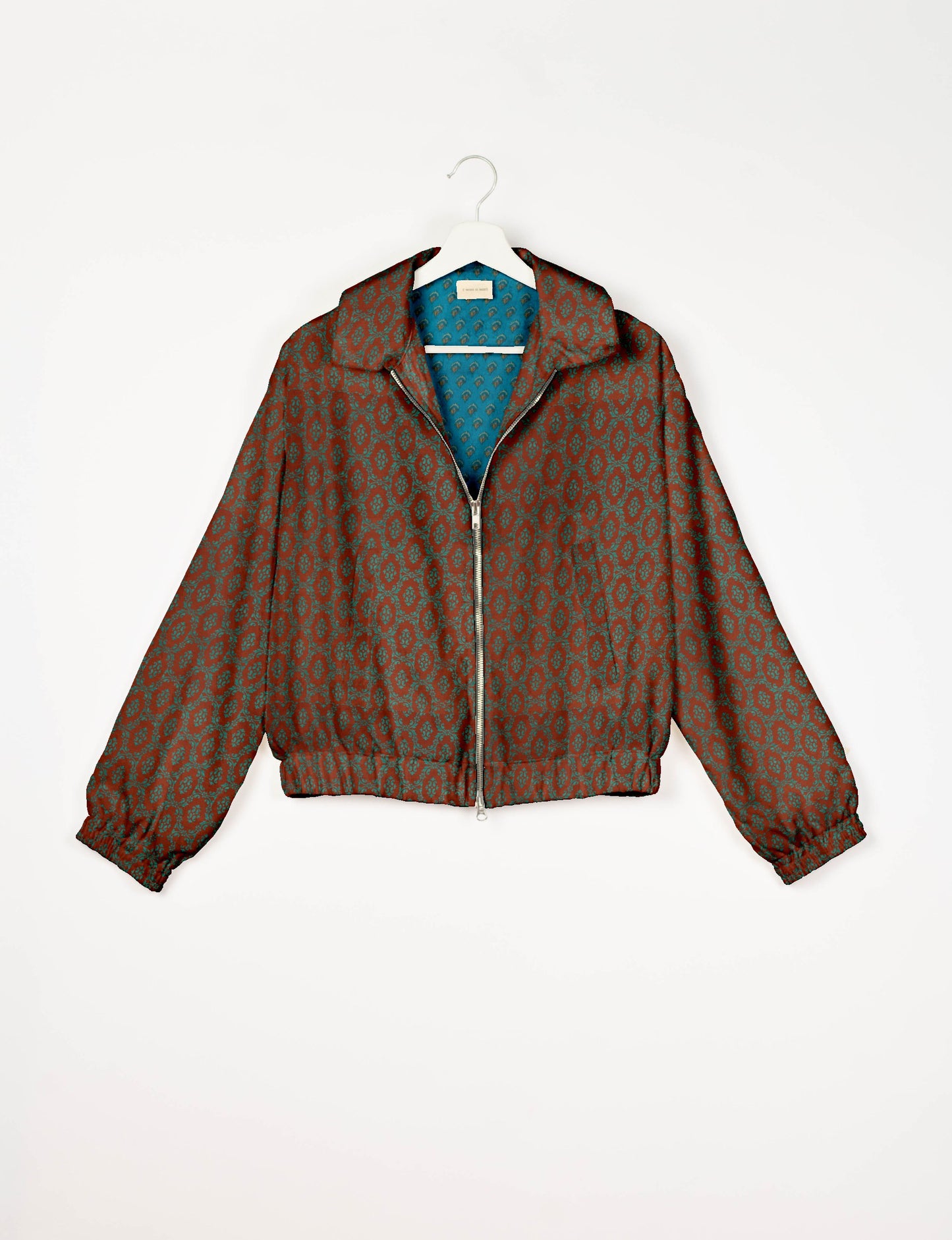 Brown bomber jacket with teal Indian ethnic pattern, front zipper, elastic cuffs and waistband, shown on white hanger front