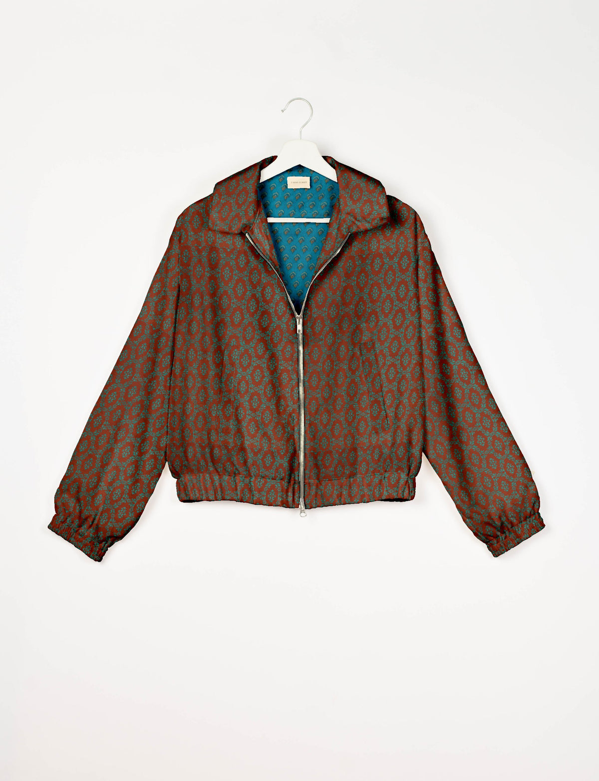 Brown bomber jacket with teal Indian ethnic pattern, front zipper, elastic cuffs and waistband, shown on white hanger front