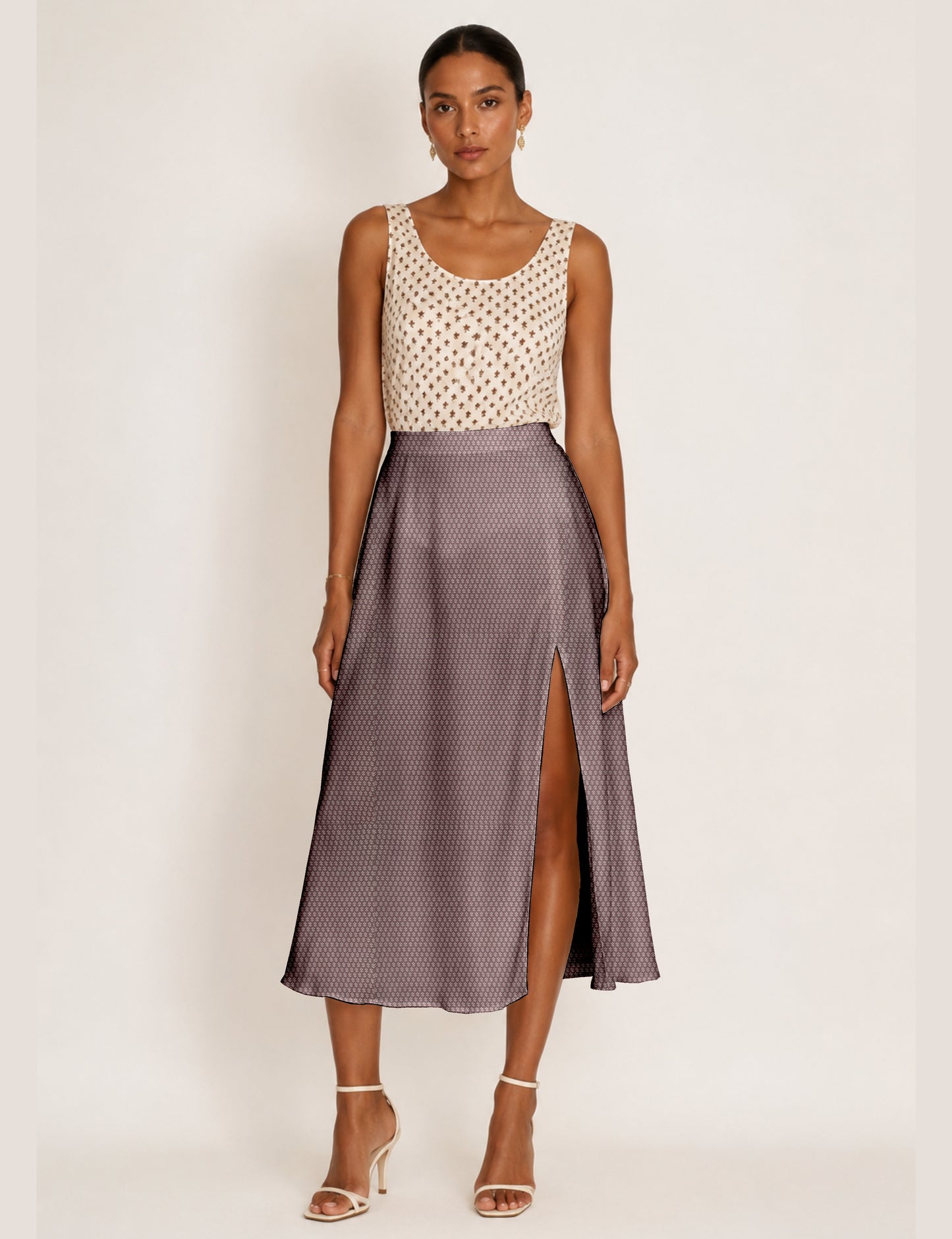 Woman wearing a yellow and black micro patterned A-line skirt with front slit, paired with beige sleeveless top and black