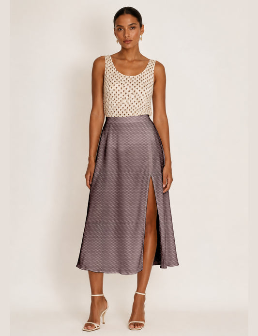 Woman wearing a yellow and black micro patterned A-line skirt with front slit, paired with beige sleeveless top and black