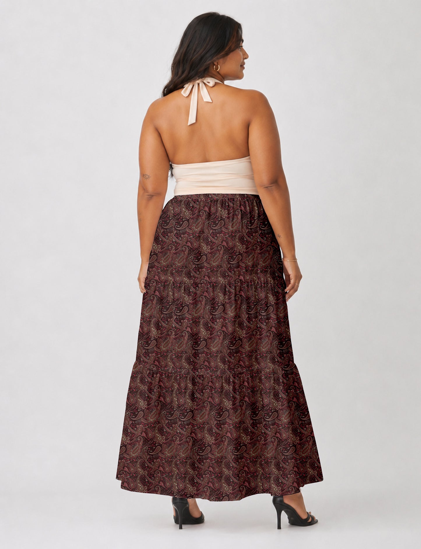 Woman wearing a yellow midi tiered skirt with a small geometric pattern, shown from the back, paired with beige top and