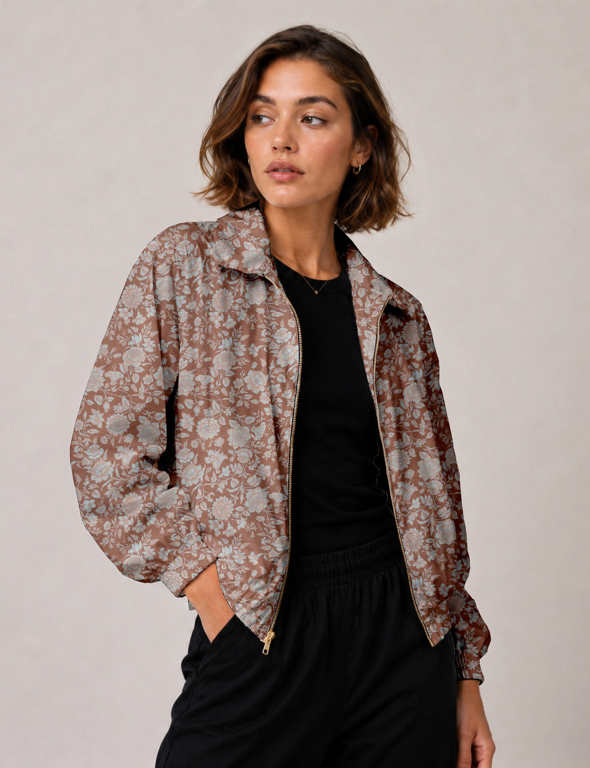Woman wearing a yellow floral bomber jacket with front zipper, elastic cuffs, and side pockets, shown from front view