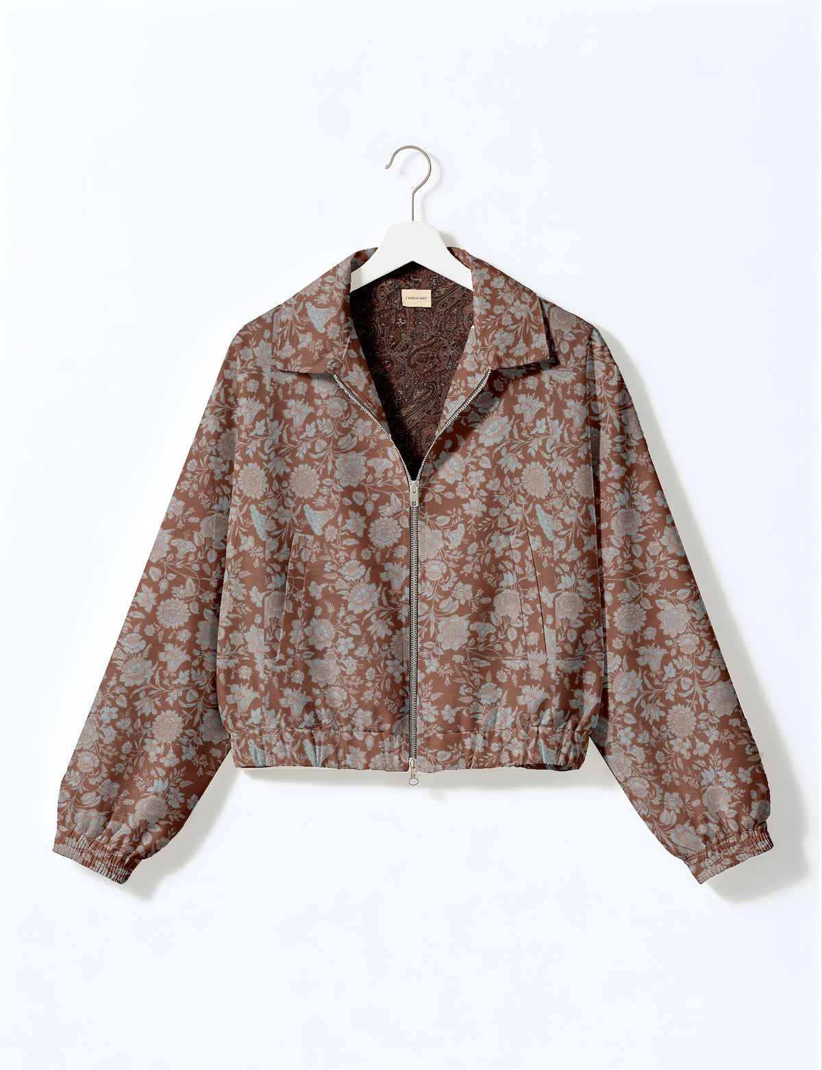 Brown floral bomber jacket with front zipper, elastic cuffs and hem, hanging on white hanger, red floral inner lining visible