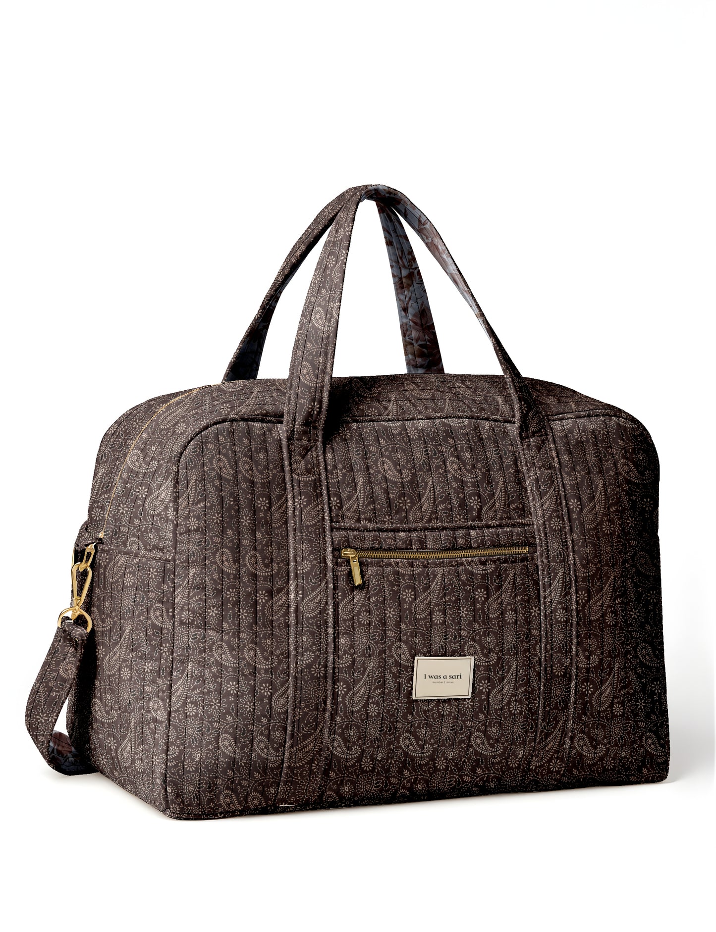 Brown quilted duffle bag with paisley pattern, front zip pocket, dual handles, and label reading "I was a sari"