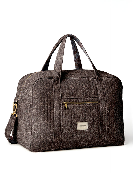 Brown quilted duffle bag with paisley pattern, front zip pocket, dual handles, and label reading "I was a sari"