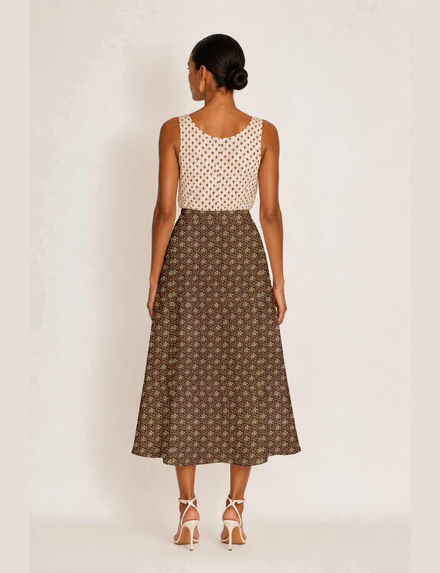 Woman wearing a yellow and black micro patterned A-line skirt with front slit, paired with beige sleeveless top and black