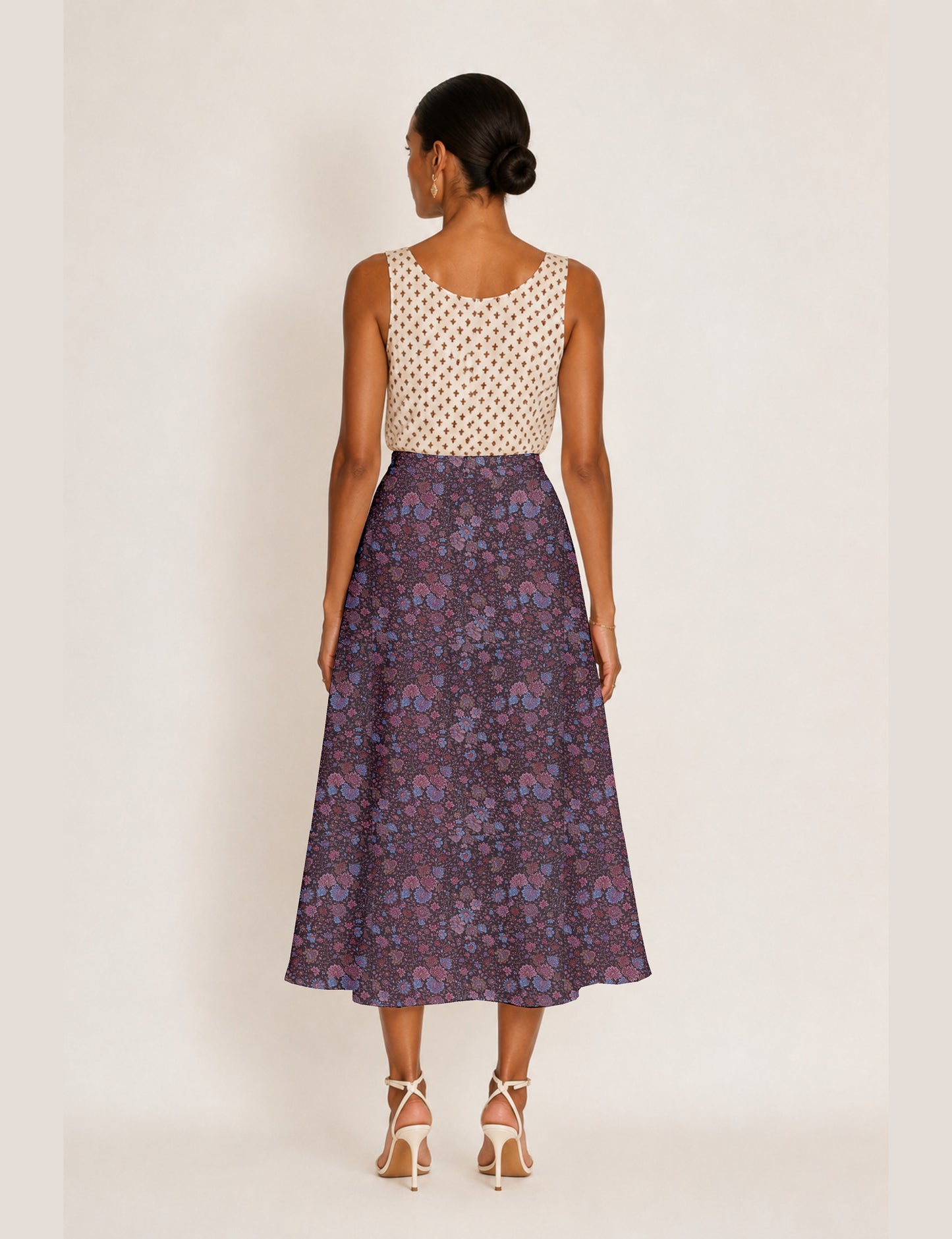 Woman wearing a yellow and black micro patterned A-line skirt with front slit, paired with beige sleeveless top and black