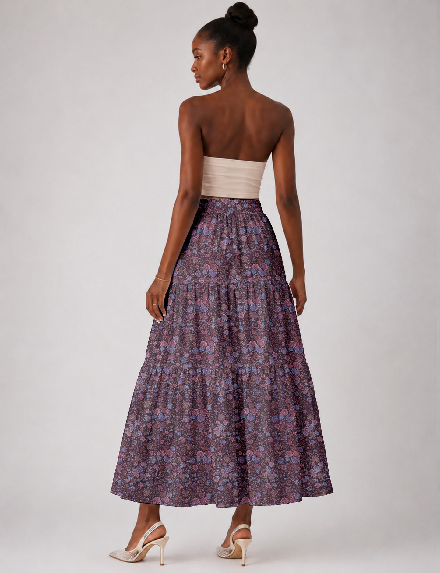Woman wearing a yellow midi tiered skirt with a small geometric pattern, paired with a beige strapless top and white heels