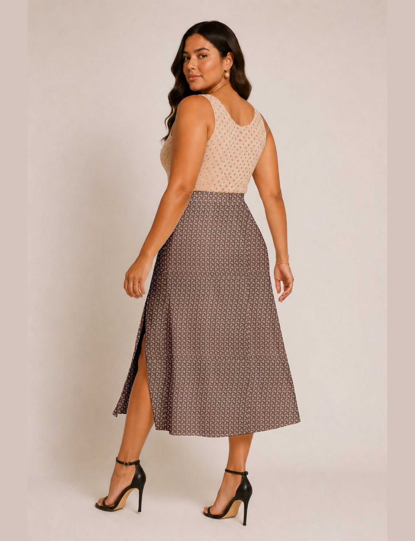 Woman wearing a yellow and black micro patterned A-line skirt with front slit, paired with beige sleeveless top and black