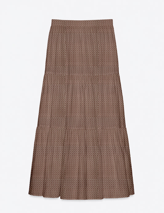 Woman wearing a yellow midi tiered skirt with a small geometric pattern, paired with a beige strapless top and white heels