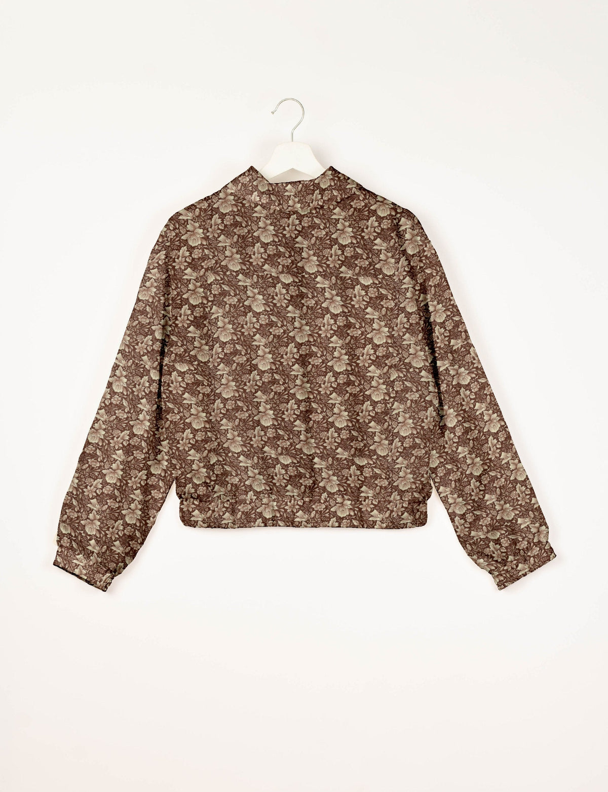 Brown bomber jacket with beige tropical floral pattern, long sleeves, elastic cuffs and waistband, shown from back on hanger