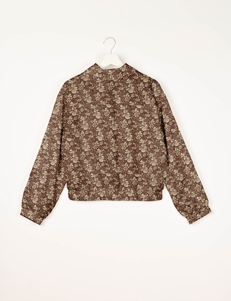 Brown bomber jacket with beige tropical floral pattern, long sleeves, elastic cuffs and waistband, shown from back on hanger