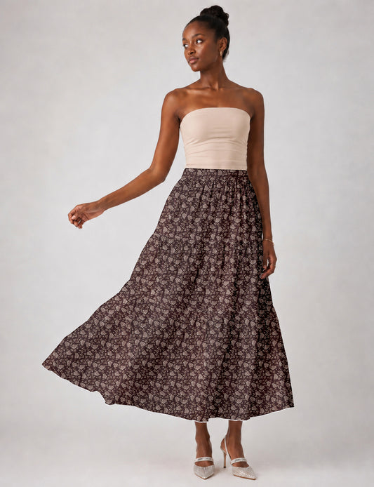 Woman wearing a yellow midi tiered skirt with a small geometric pattern, paired with a beige strapless top and white heels