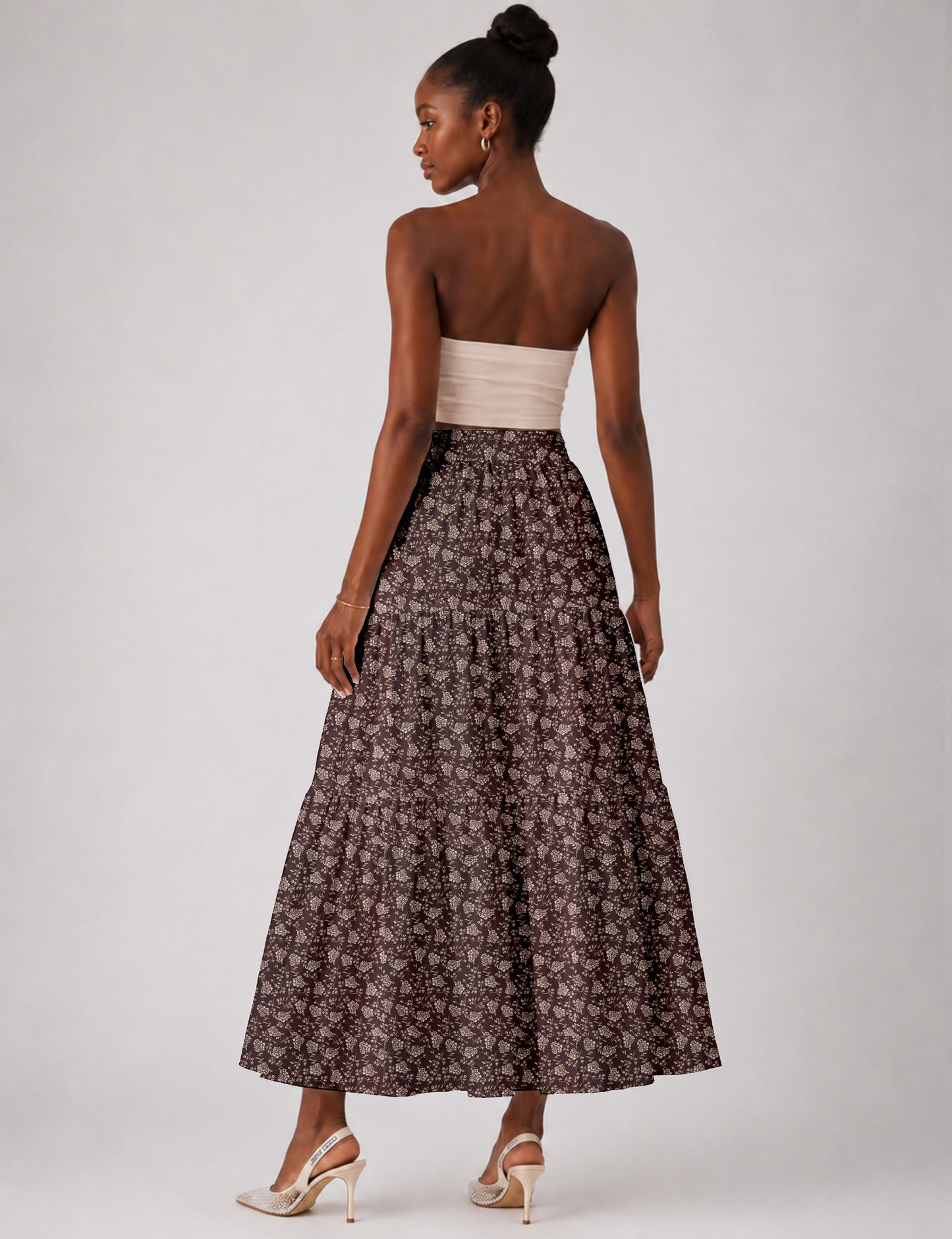Woman wearing a yellow midi tiered skirt with a small geometric pattern, shown from the back, paired with beige top and