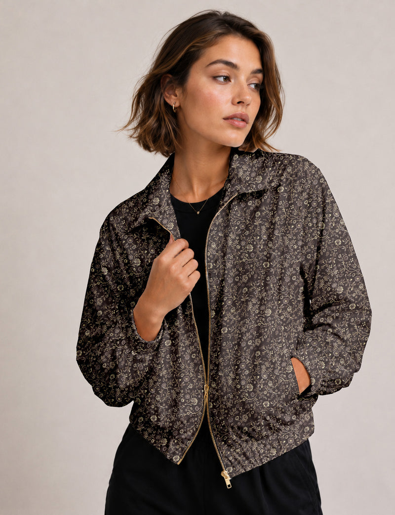 Woman wearing a yellow floral bomber jacket with front zipper, elastic cuffs, and side pockets, shown from front view