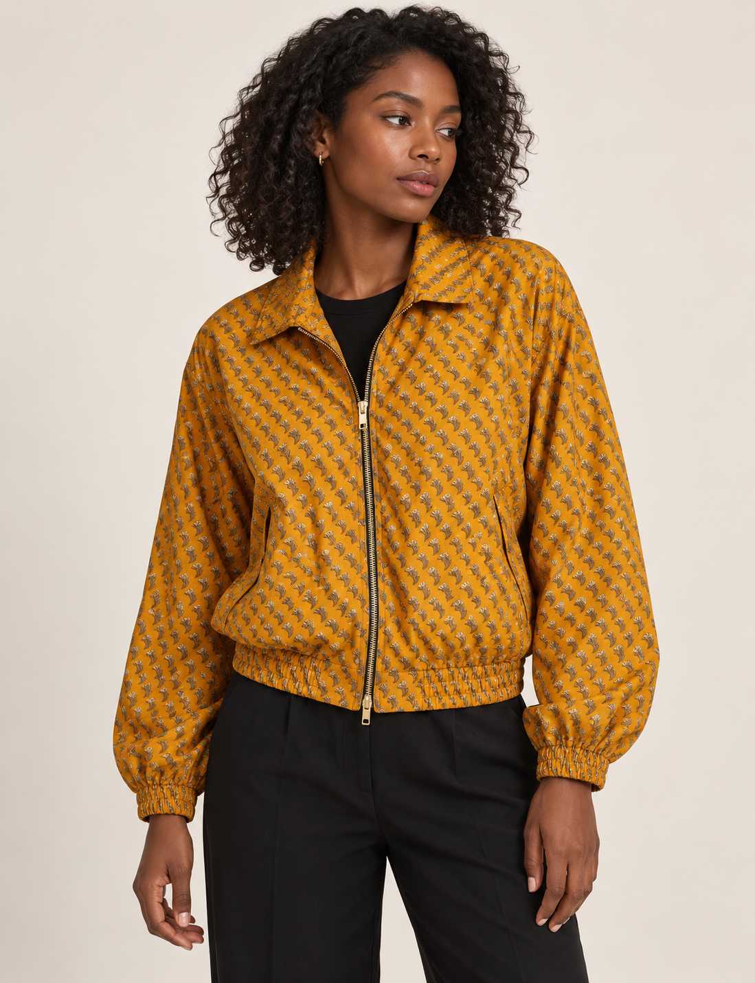 Woman wearing a yellow floral bomber jacket with front zipper, elastic cuffs, and side pockets, shown from front view