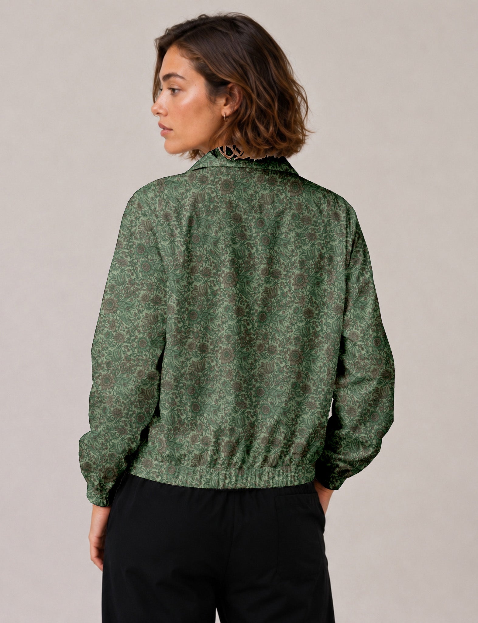 Woman wearing a yellow floral bomber jacket with front zipper, elastic cuffs, and side pockets, shown from front view