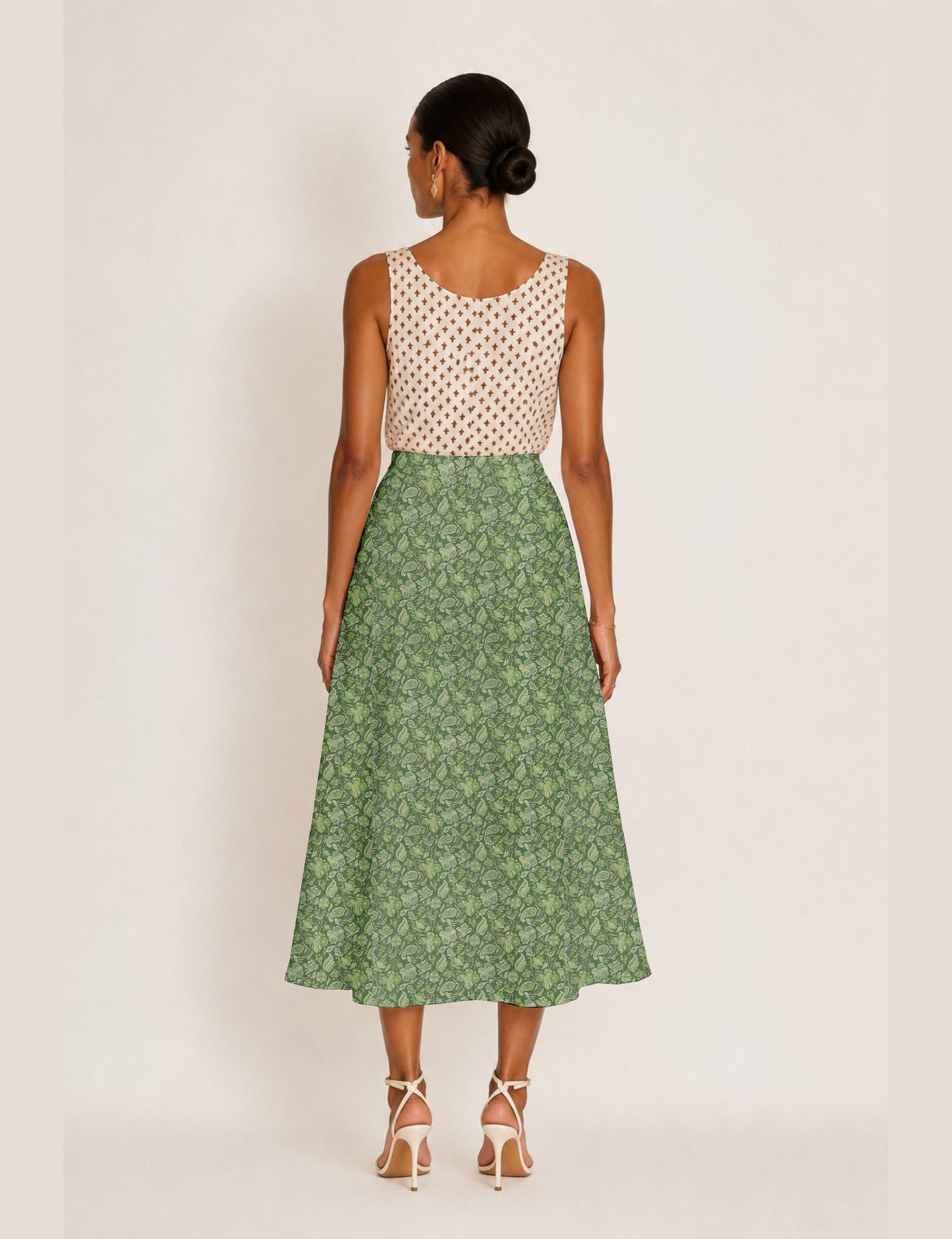 Woman wearing a yellow and black micro patterned A-line skirt with front slit, paired with beige sleeveless top and black