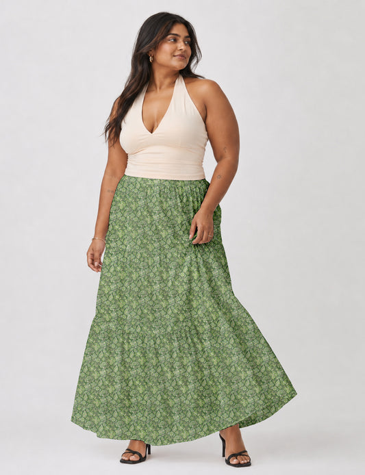 Woman wearing a yellow midi tiered skirt with a small geometric pattern, paired with a beige strapless top and white heels