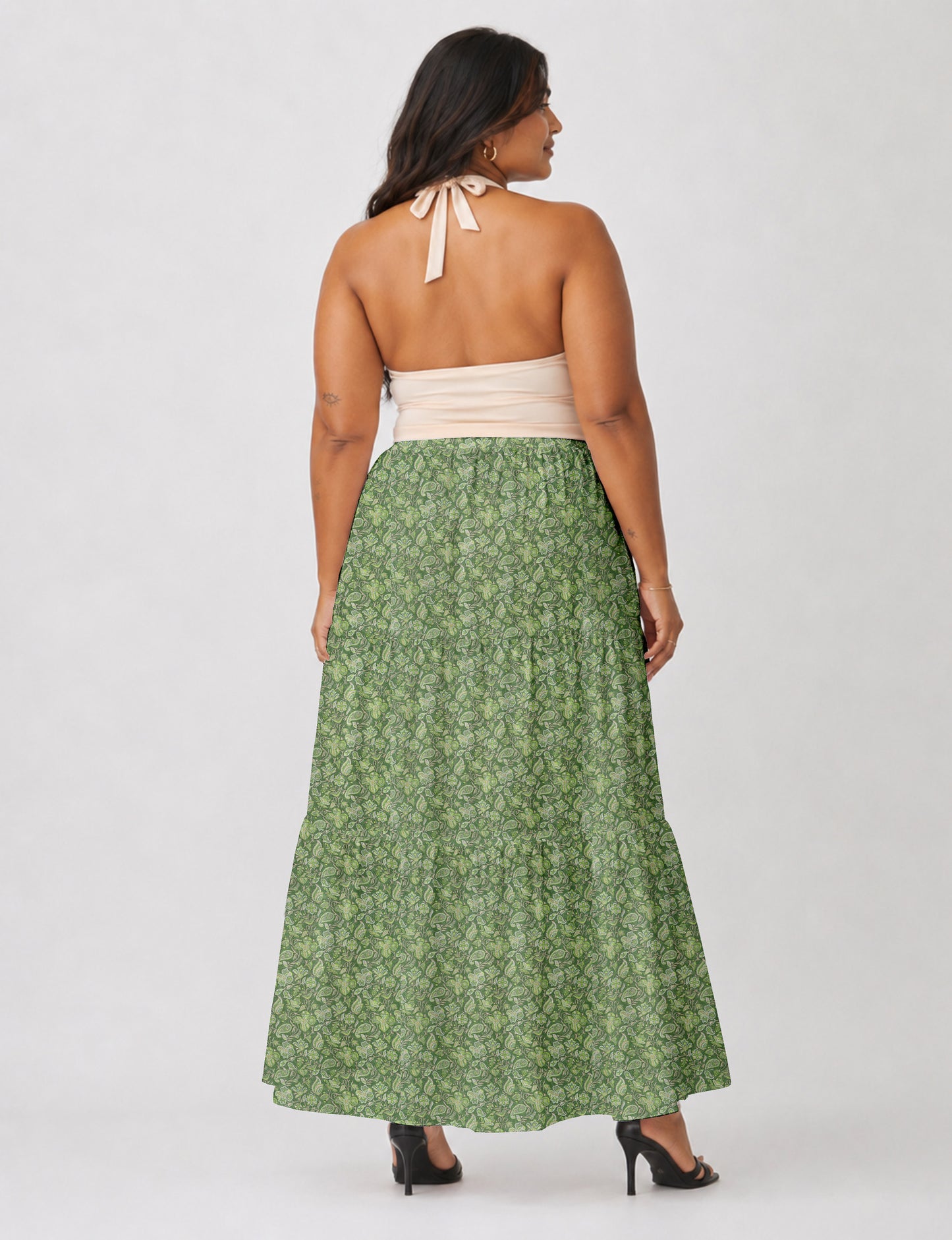 Woman wearing a yellow midi tiered skirt with a small geometric pattern, shown from the back, paired with beige top and