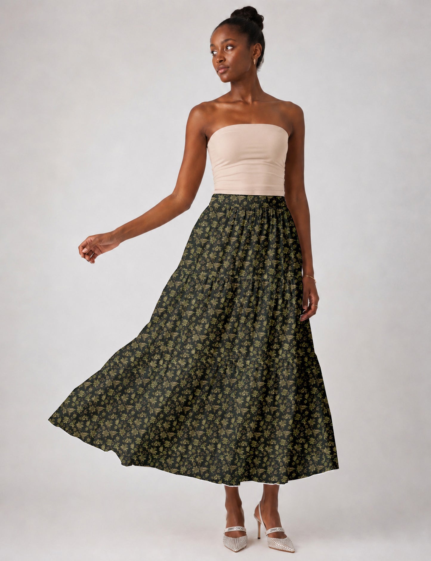 Woman wearing a yellow midi tiered skirt with a small geometric pattern, paired with a beige strapless top and white heels