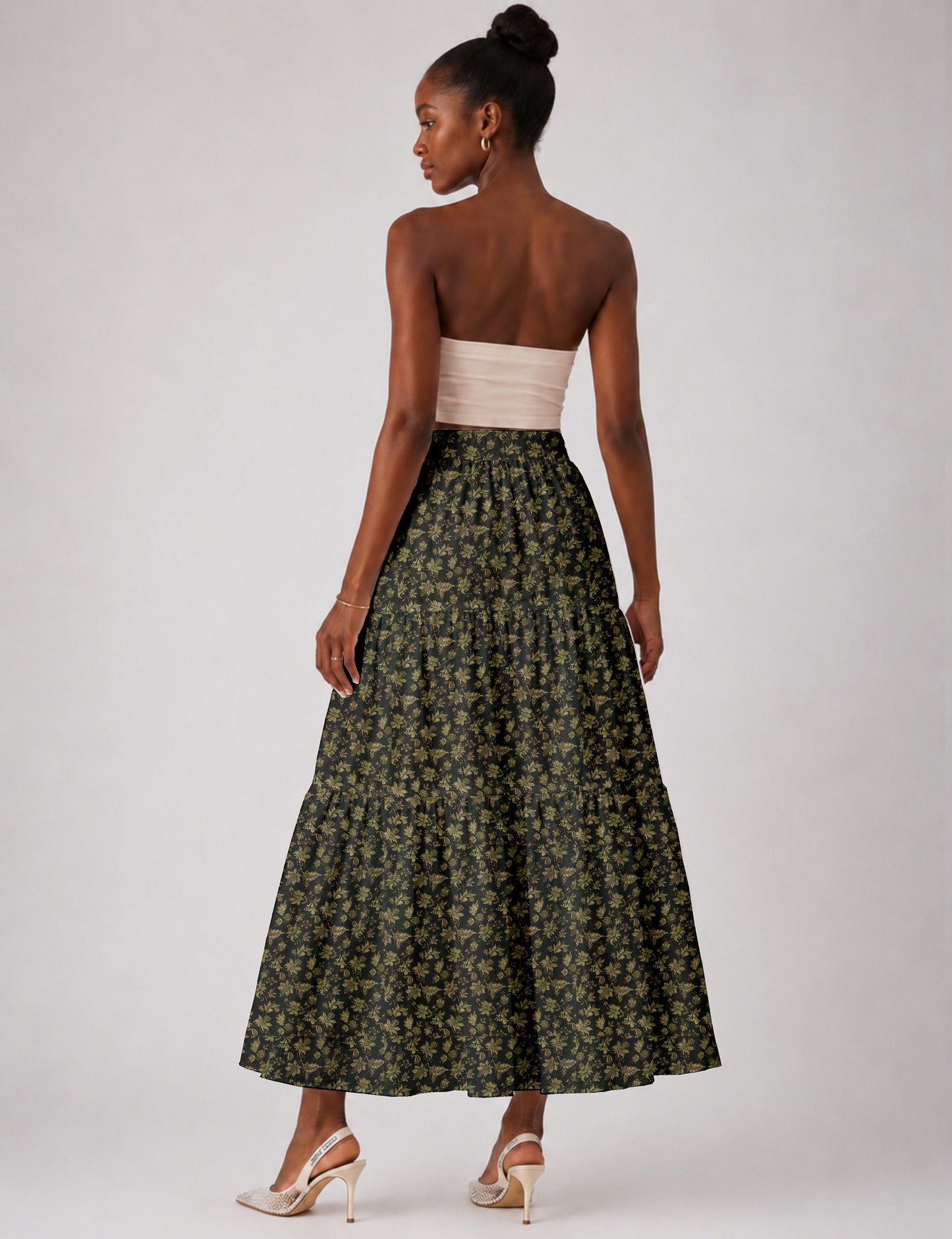 Woman wearing a yellow midi tiered skirt with a small geometric pattern, shown from the back, paired with beige top and
