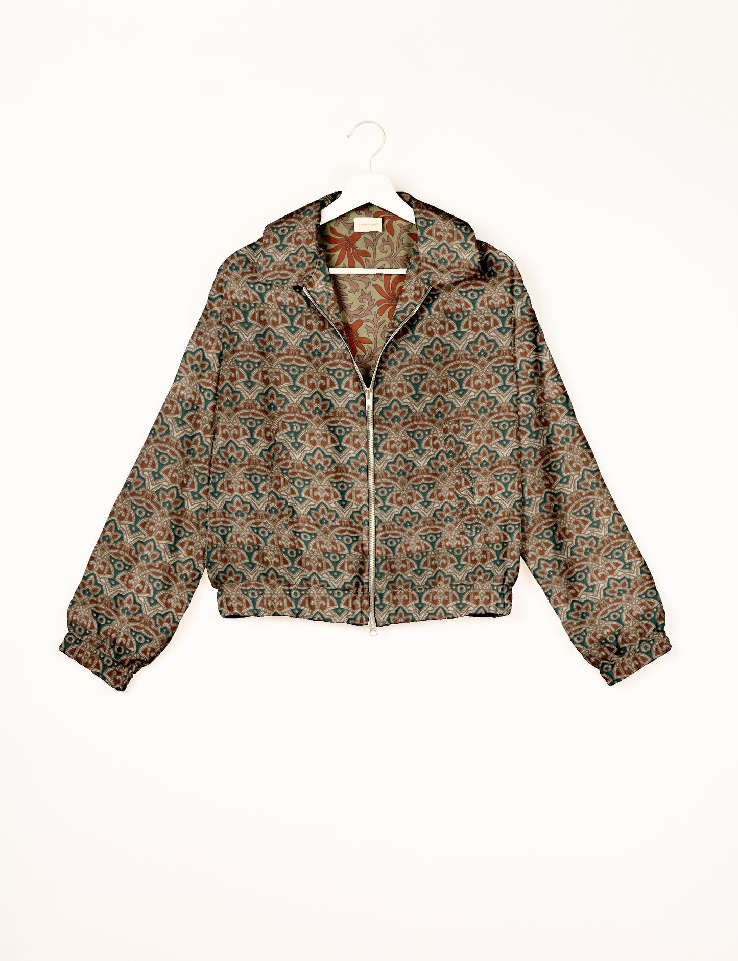 Green bomber jacket with Indian ethnic floral and geometric patterns, front zipper, and elastic cuffs, shown on hanger