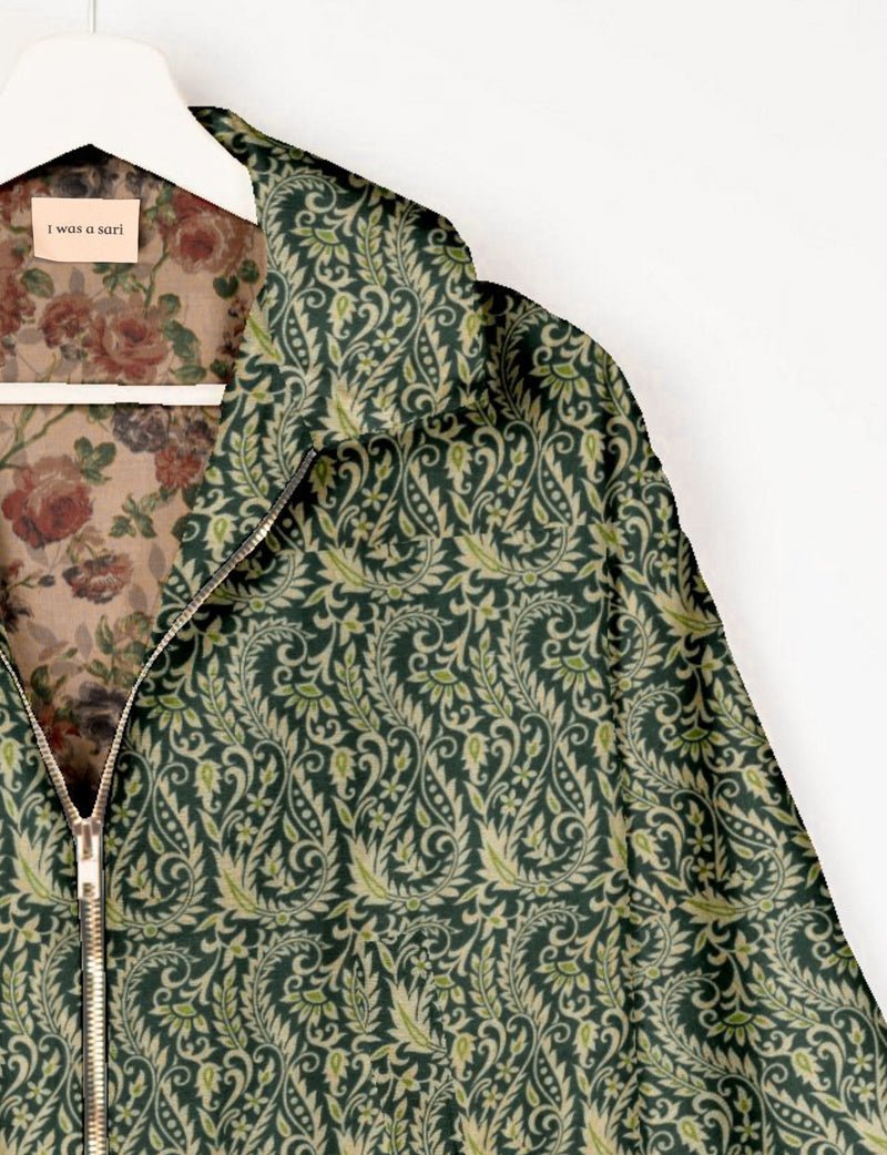 Green bomber jacket with cream and light green leaf and vine pattern, silver zipper, floral inner lining, label reading "I
