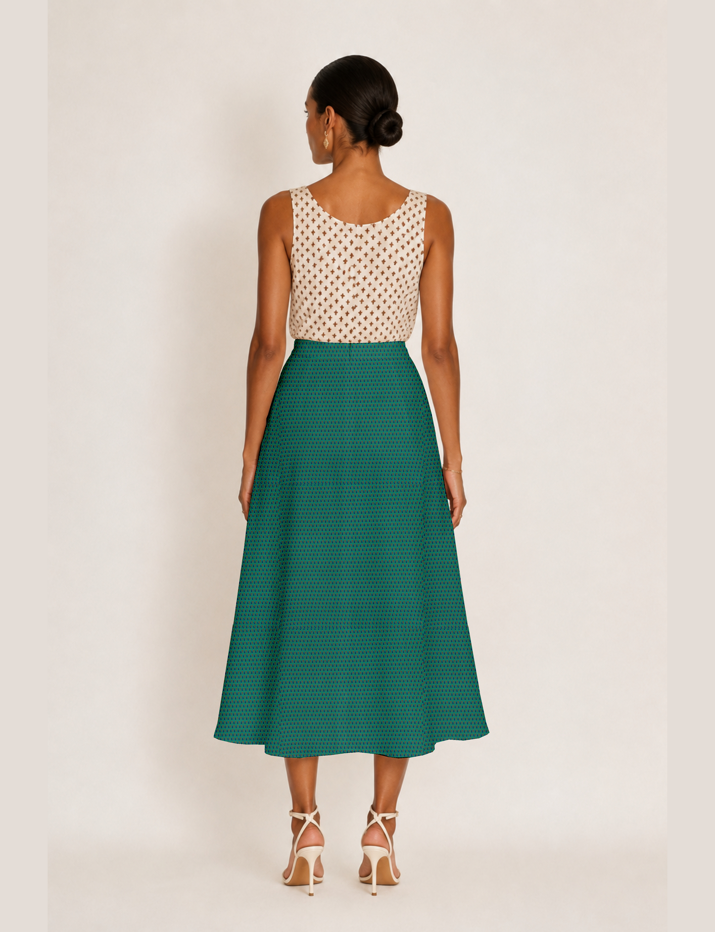 Woman wearing a yellow and black micro patterned A-line skirt with front slit, paired with beige sleeveless top and black