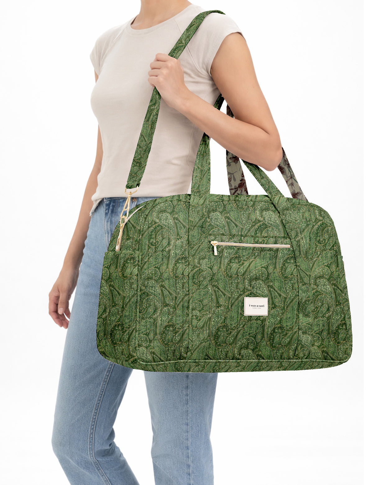 Brown quilted duffle bag with paisley pattern, front zip pocket, dual handles, and label reading "I was a sari"
