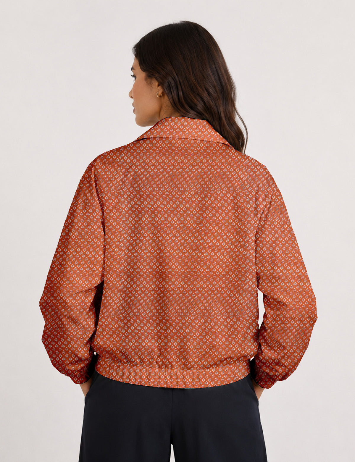 Brown floral bomber jacket with front zipper, elastic cuffs and hem, hanging on white hanger, red floral inner lining visible