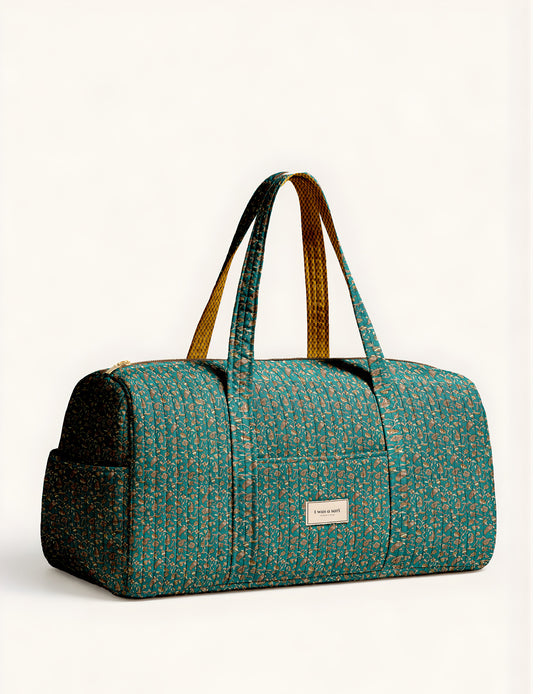 Quilted brown paisley barrel bag with double handles, front pocket, and gold zipper, shown in side angle view