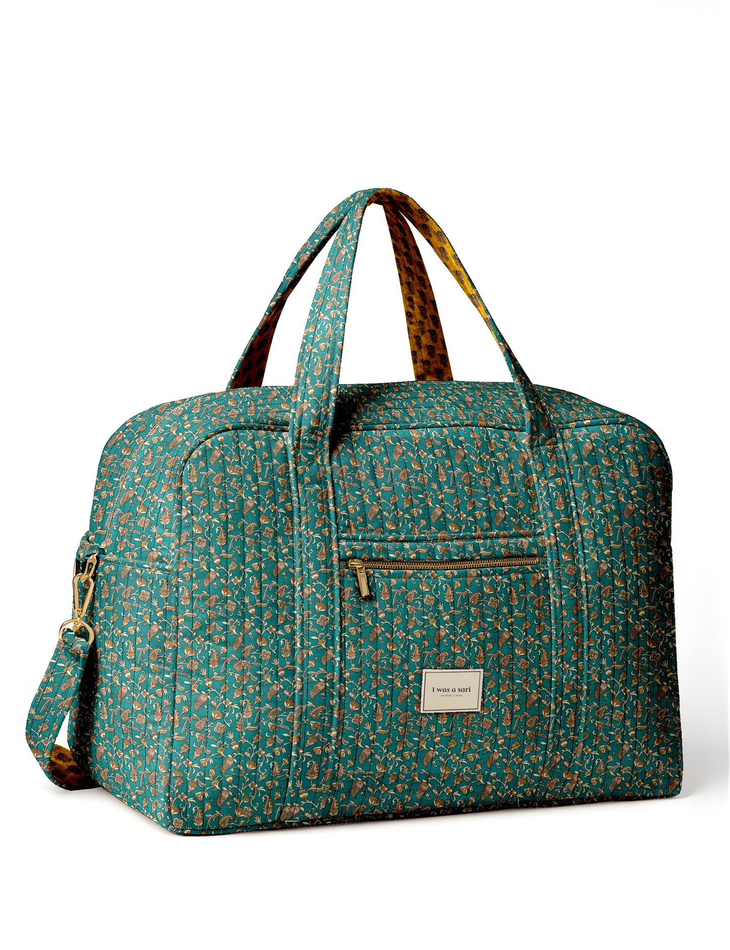 Brown quilted duffle bag with paisley pattern, front zip pocket, dual handles, and label reading "I was a sari"