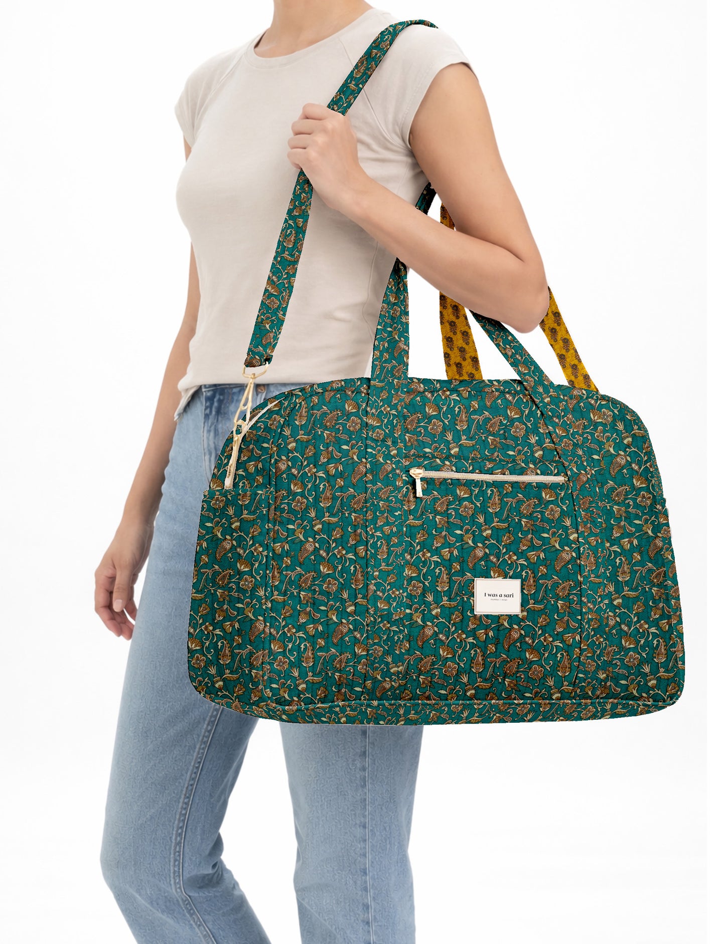 Brown quilted duffle bag with paisley pattern, front zip pocket, dual handles, and label reading "I was a sari"