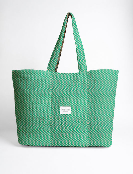 Quilted yellow tropical patterned beach bag with long handles and white label reading "I was a sari" front view