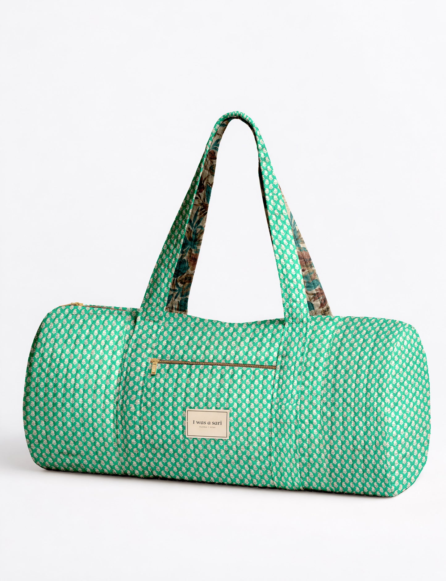 Brown paisley quilted bowling bag with front zipper pocket, held by person wearing white shirt and light blue jeans