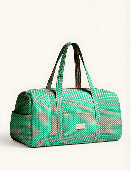 Quilted brown paisley barrel bag with double handles, front pocket, and gold zipper, shown in side angle view