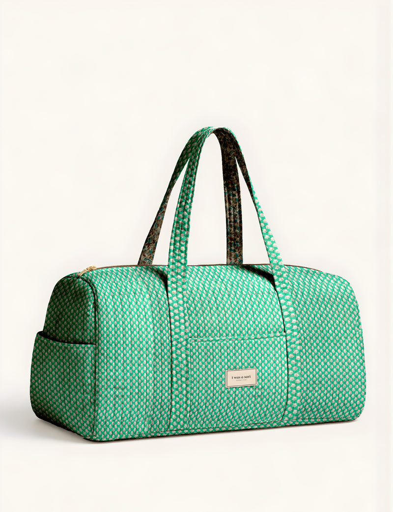 Quilted brown paisley barrel bag with double handles, front pocket, and gold zipper, shown in side angle view