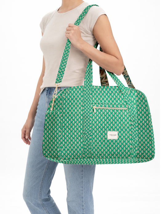 Brown quilted duffle bag with paisley pattern, front zip pocket, dual handles, and label reading "I was a sari"