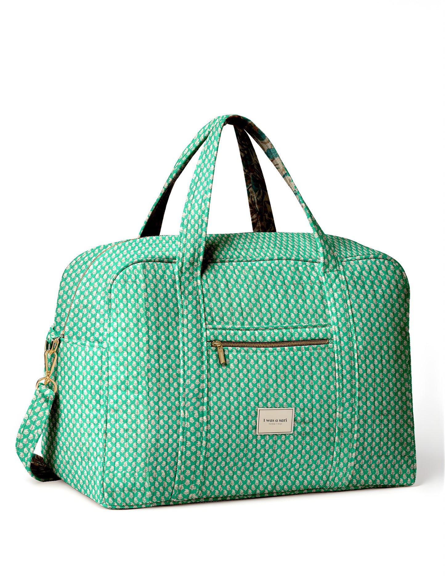Brown quilted duffle bag with paisley pattern, front zip pocket, dual handles, and label reading "I was a sari"