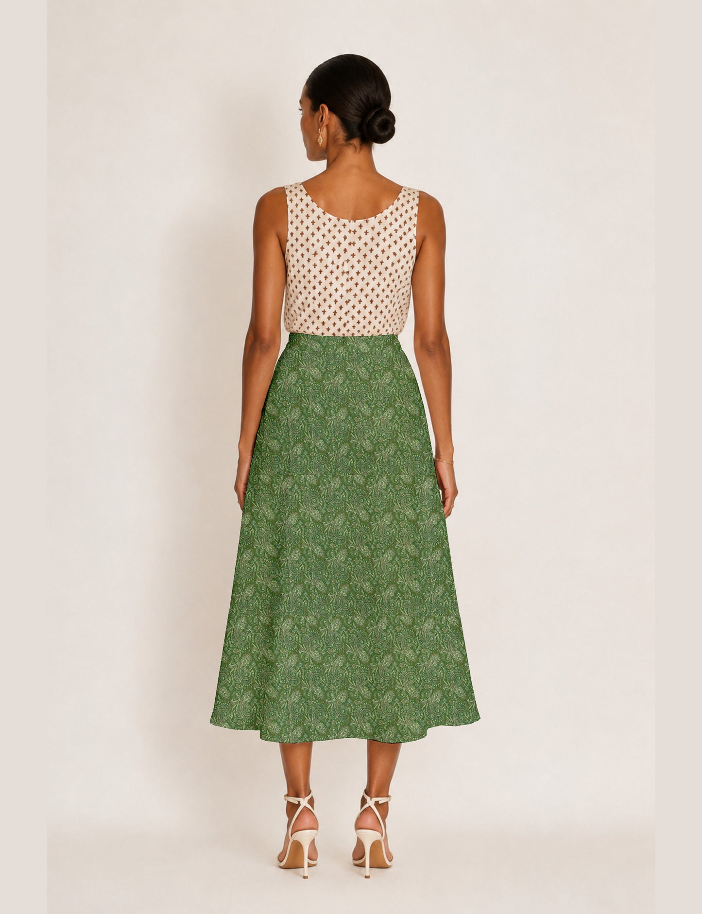 Woman wearing a yellow and black micro patterned A-line skirt with front slit, paired with beige sleeveless top and black