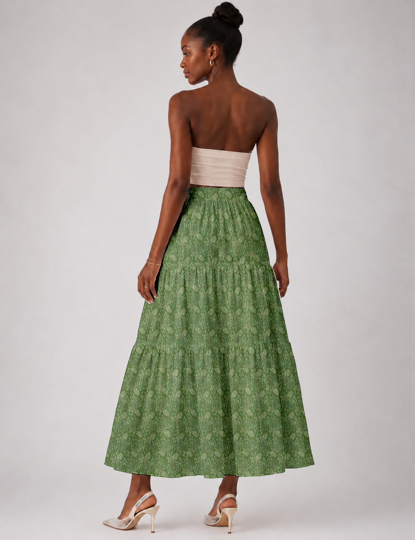 Woman wearing a yellow midi tiered skirt with a small geometric pattern, paired with a beige strapless top and white heels