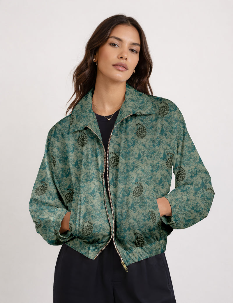 Woman wearing a yellow floral bomber jacket with front zipper, elastic cuffs, and side pockets, shown from front view