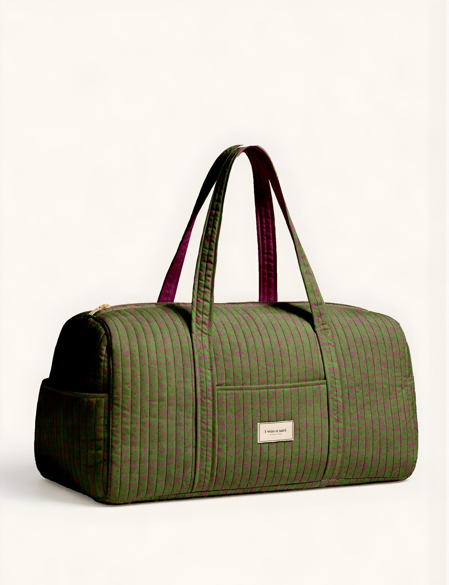 Quilted brown paisley barrel bag with double handles, front pocket, and gold zipper, shown in side angle view