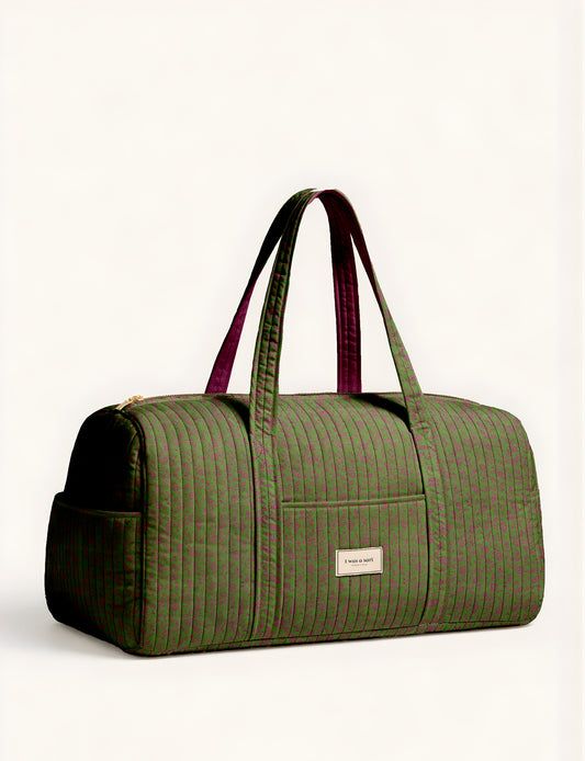 Quilted brown paisley barrel bag with double handles, front pocket, and gold zipper, shown in side angle view