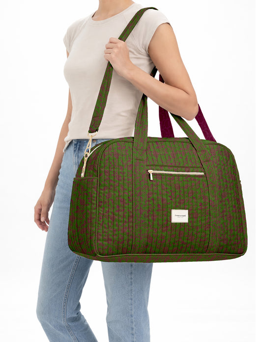 Brown quilted duffle bag with paisley pattern, front zip pocket, dual handles, and label reading "I was a sari"